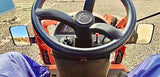 A driver inside a tractor, hands on the wheel, ready to navigate through a field.